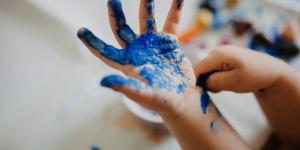 child with blue paint on their hand